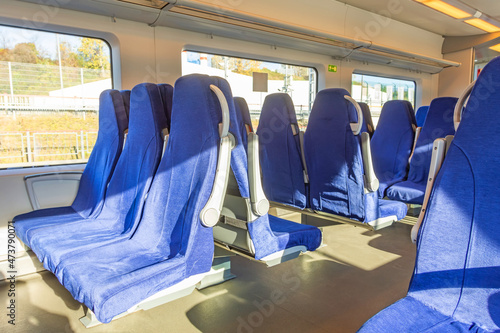 Interior of a passenger train with empty blue seats. © aapsky