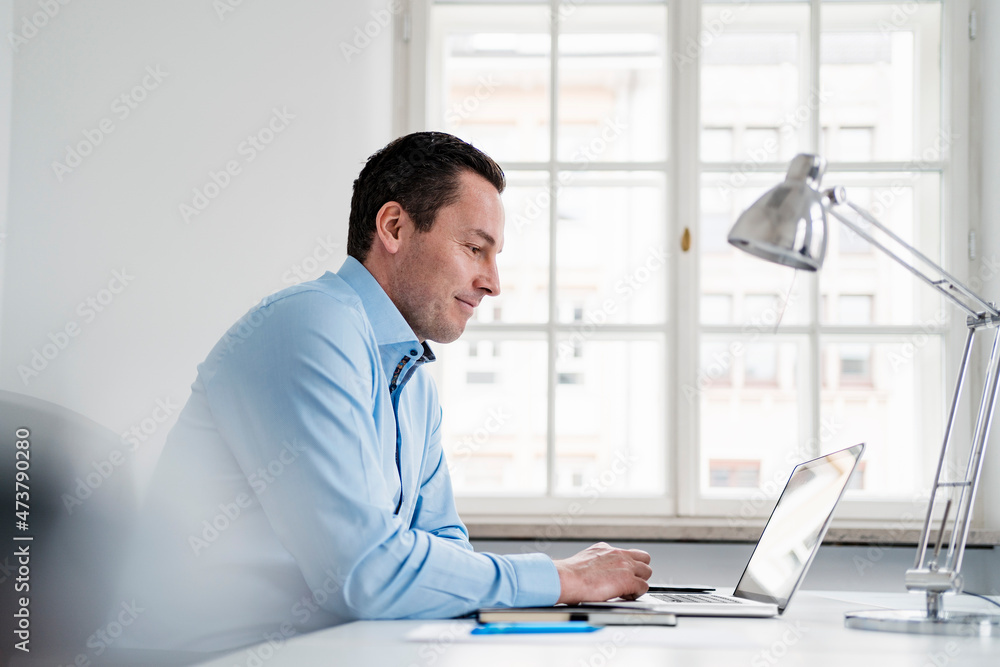 Male entrepreneur using laptop on desk at workplace Male entrepreneur using laptop on desk at workplace