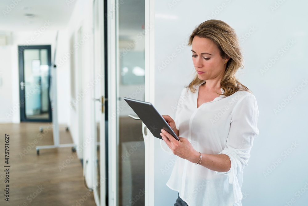 Businesswoman using digital tablet by soundproof cabin in office Businesswoman using digital tablet by soundproof cabin in office