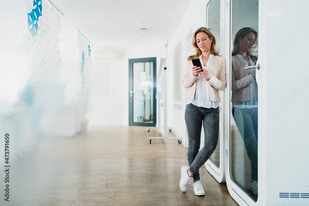 Businesswoman texting through mobile phone in office