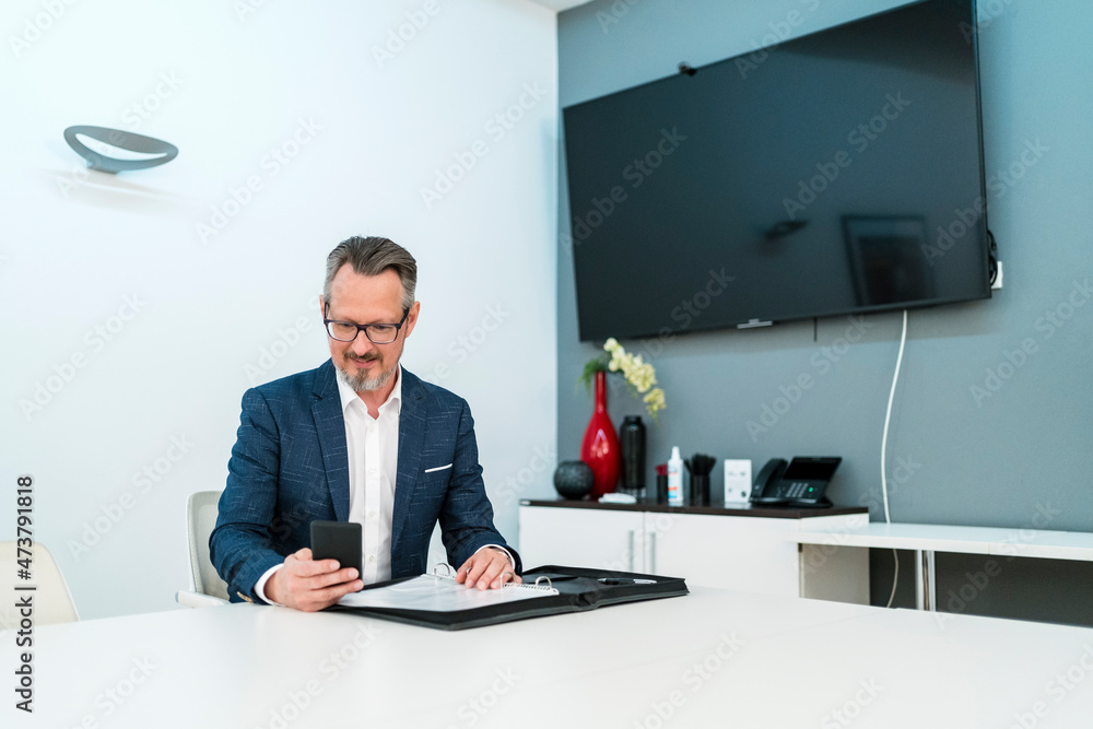 Male entrepreneur using mobile phone while sitting at office Male entrepreneur using mobile phone while sitting at office