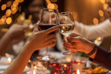 holidays, drinks and celebration concept - close up of hands toasting wine glasses at dinner party on christmas at home
