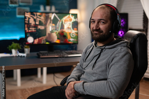 Portrait of streamer getting ready to play video games on computer. Gamer with headphones preparing to stream live gameplay, playing with keyboard and mousepad on monitor. Player streaming