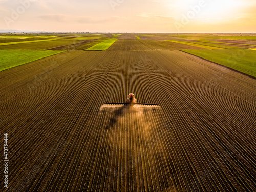Aerial view of tractor spraying soybean crops at sunset photo