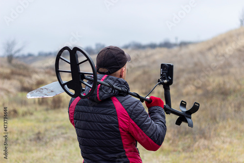 Konstfotografi a man with a metal detector and a shovel, view from the back