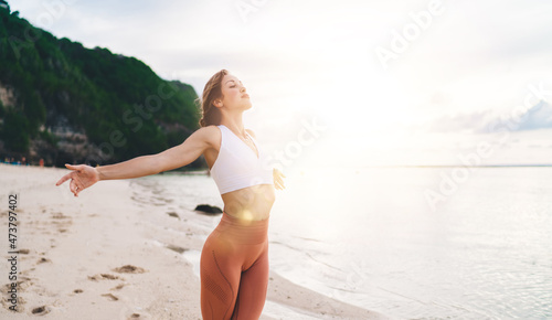 Fit woman with closed eyes feeling alive on sandy beach