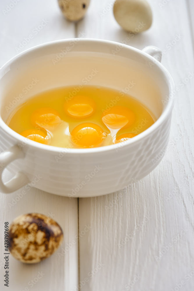 Fresh and useful quail eggs in a white cup on a white wooden table close-up Fresh and useful quail eggs in a white cup on a white wooden table close-up