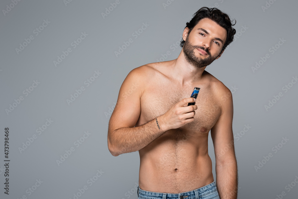 Fototapeta premium young shirtless man holding electric razor isolated on grey