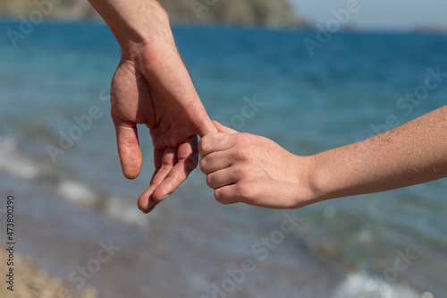 Couple hands held together on a natural sea background, close up