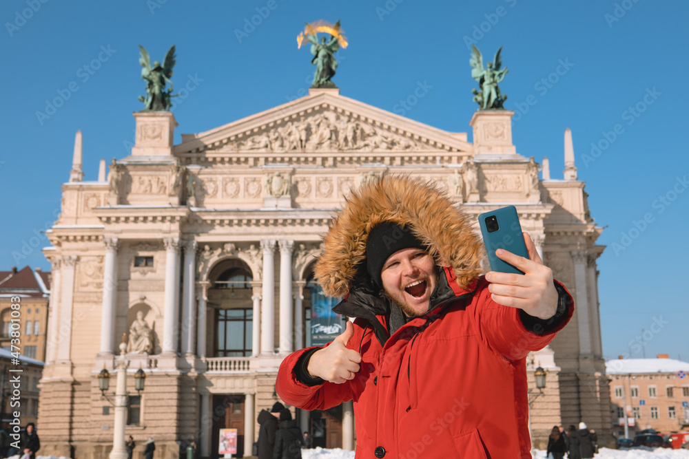 smiling man taking selfie in front of opera building