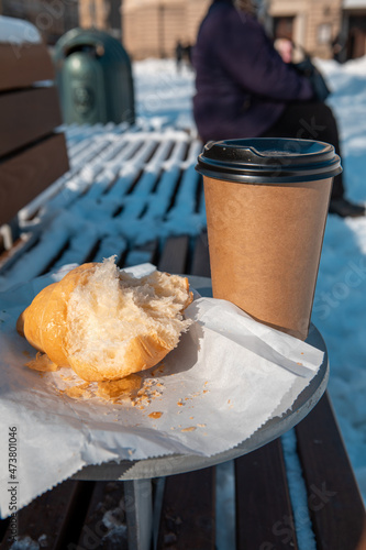 outdoors table with bench coffee to go and croissant