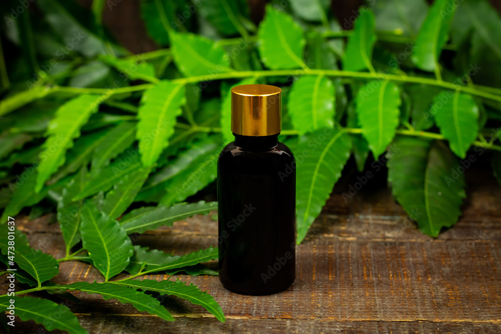 Neem oil in bottle and neem leaf with branch on wooden background. Neem oil in bottle and neem leaf with branch on wooden background.