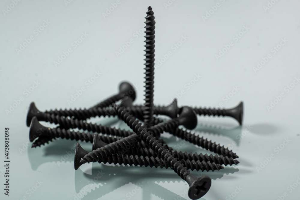 black self-tapping screw for wood next to a piece of wood black self-tapping screw for wood next to a piece of wood