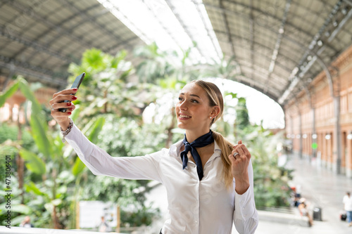 Smiling flight attendant taking selfie on mobile phone in garden