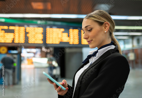 Young air stewardess using smart phone at airport