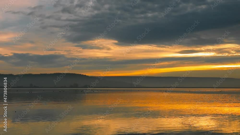 Stunning sunrise at the lake with reflections and colored clouds during autumn Stunning sunrise at the lake with reflections and colored clouds during autumn