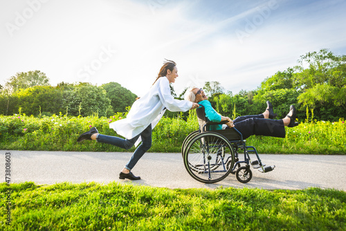 Senior woman in wheelchair enjoying with caretaker in park