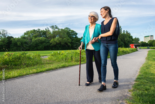 Smiling senior woman with mid-adult woman on footpath in park