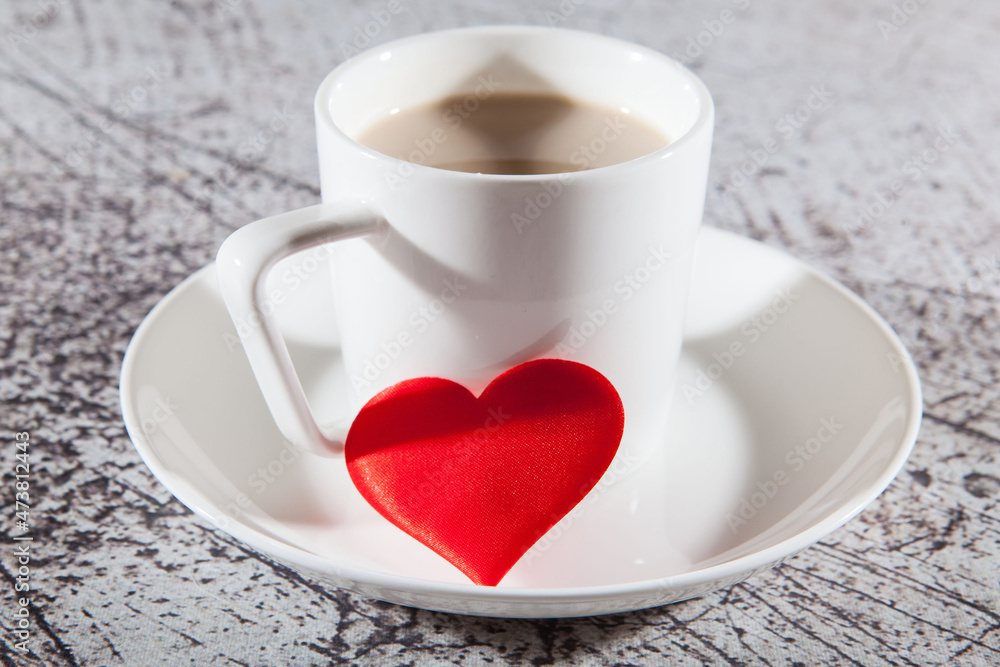 A mug of coffee and red heart on a glass saucer