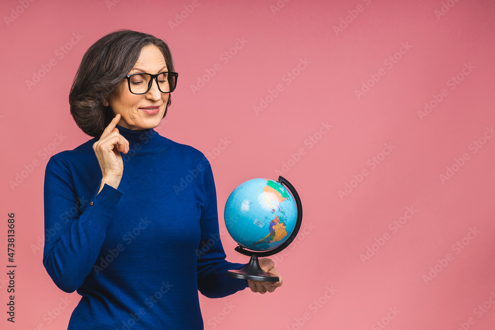 Traveler tourist pensive mature elderly senior lady woman holding in hands Earth world globe isolated on  pink background studio portrait. Copy space for text.