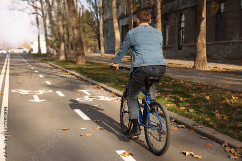 Fototapeta Naklejka Na Ścianę i Meble -  Man riding bicycle on lane in city, back view