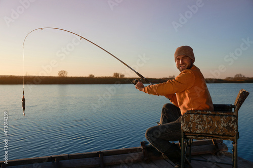 Fisherman catching fish with rod at riverside