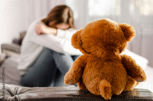 Sitting upset woman and teddy bear. Selective focus. Break up concept photo