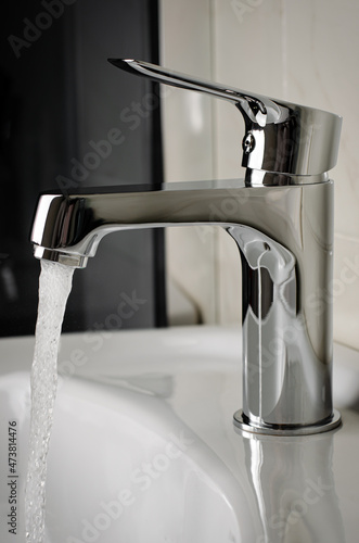 Water flows from the tap or faucet in bathroom. Vertical, close up