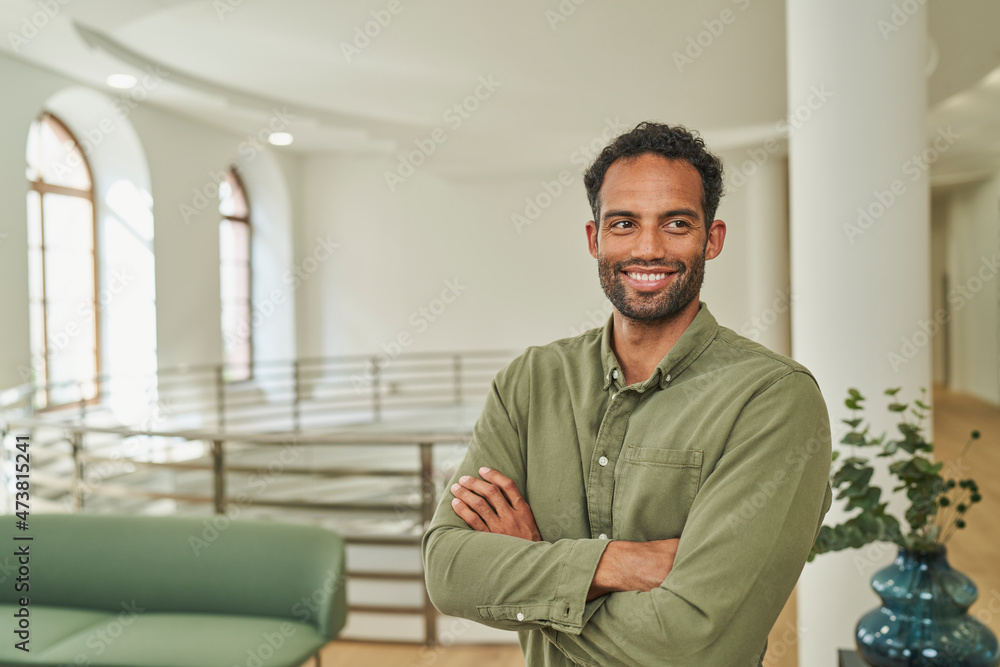 Businessman with arms crossed smiling at office lobby Businessman with arms crossed smiling at office lobby