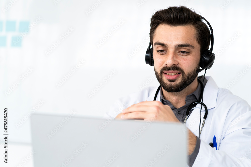 Male doctor wearing headphone while discussing on video conference at hospital Male doctor wearing headphone while discussing on video conference at hospital