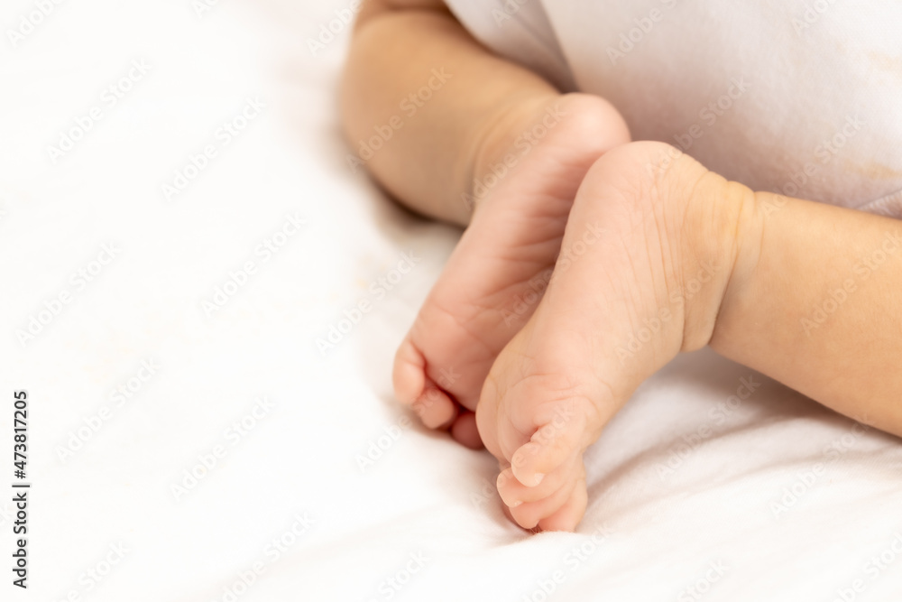 close up asian woman small baby infant feet while sleeping on soft bed covered with white cloth. close up asian woman small baby infant feet while sleeping on soft bed covered with white cloth.