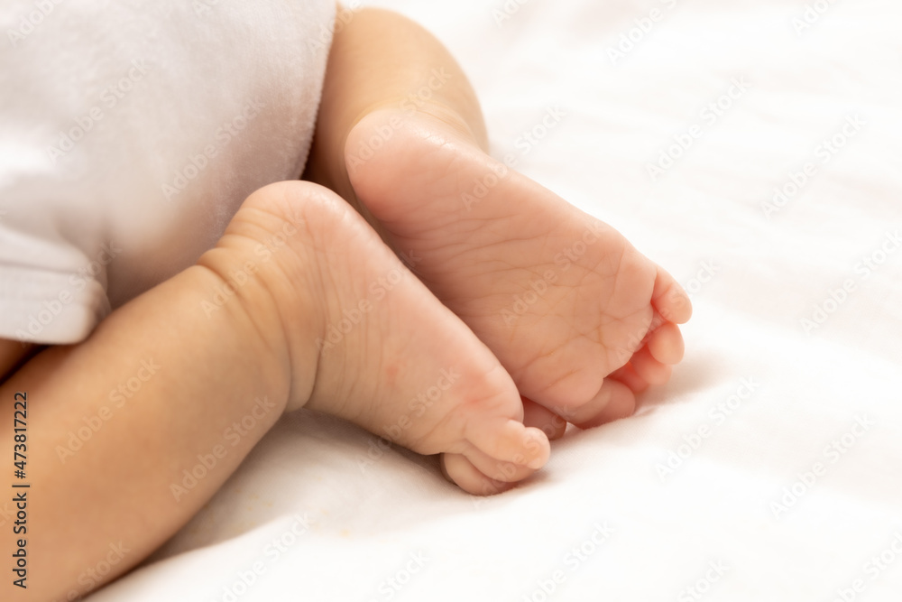 close up asian woman small baby infant feet while sleeping on soft bed covered with white cloth. close up asian woman small baby infant feet while sleeping on soft bed covered with white cloth.