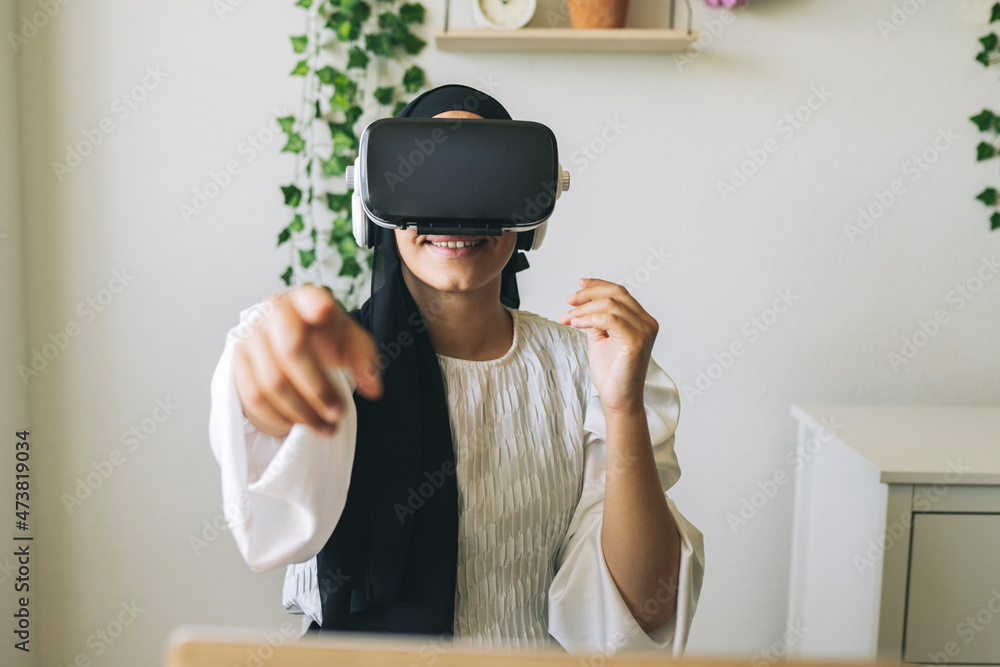 Smiling female freelance worker pointing while using virtual reality headset at home Smiling female freelance worker pointing while using virtual reality headset at home