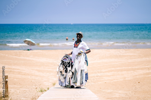 Male vendor standing on boardwalk while selling clothes at beach during sunny day photo