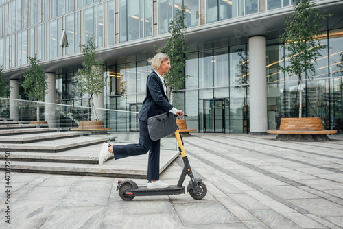 Businesswoman riding electric push scooter in office park photo