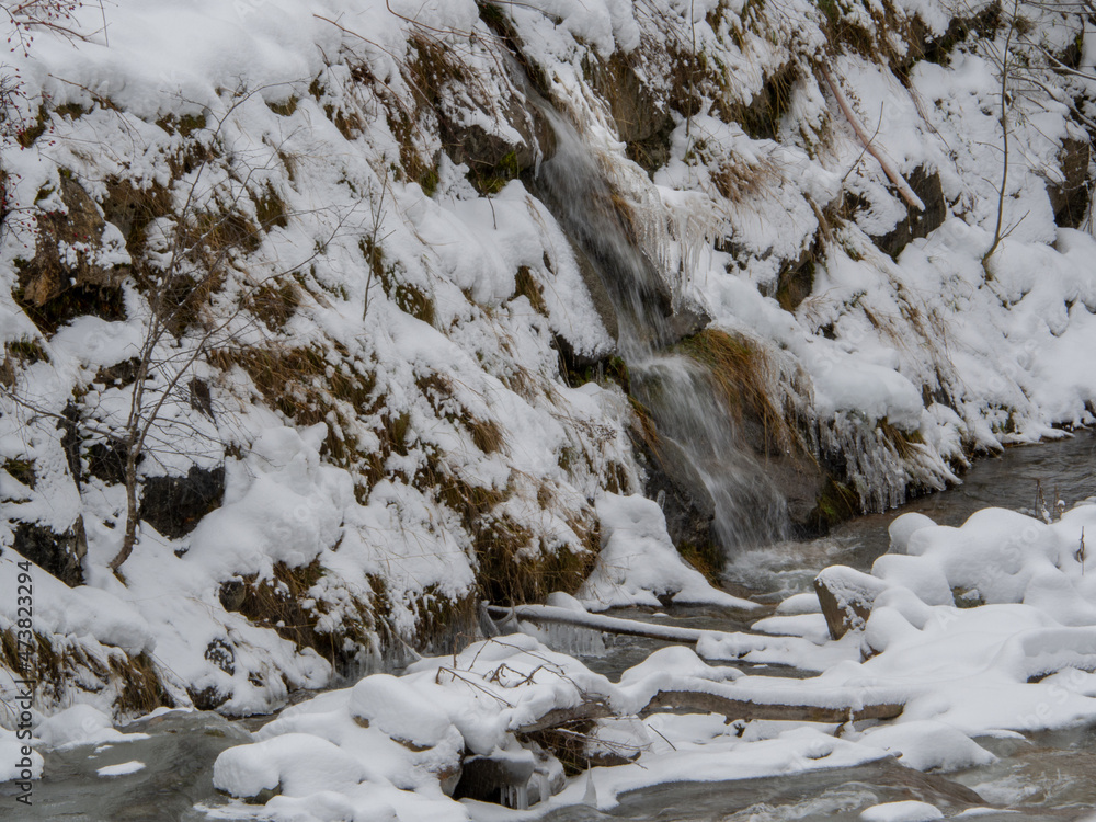 A frozen waterfall with ice in a blue and white color in winter. Winter background. A frozen waterfall with ice in a blue and white color in winter. Winter background.