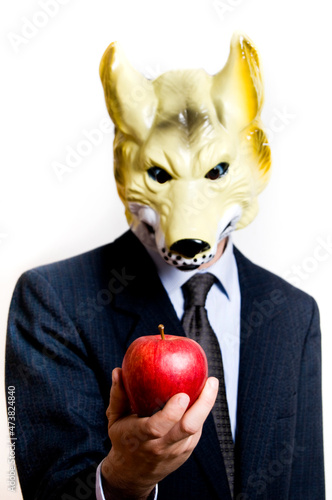 businessman with wolf mask offering a red apple  - temptation and corruption in business concept