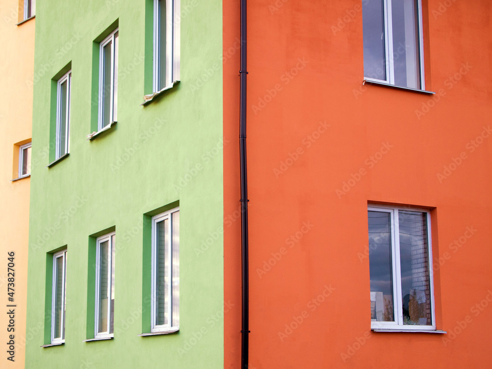 Part of a bright colorful house. The walls of the building are painted with different colors (orange, green, yellow). Abstract background.