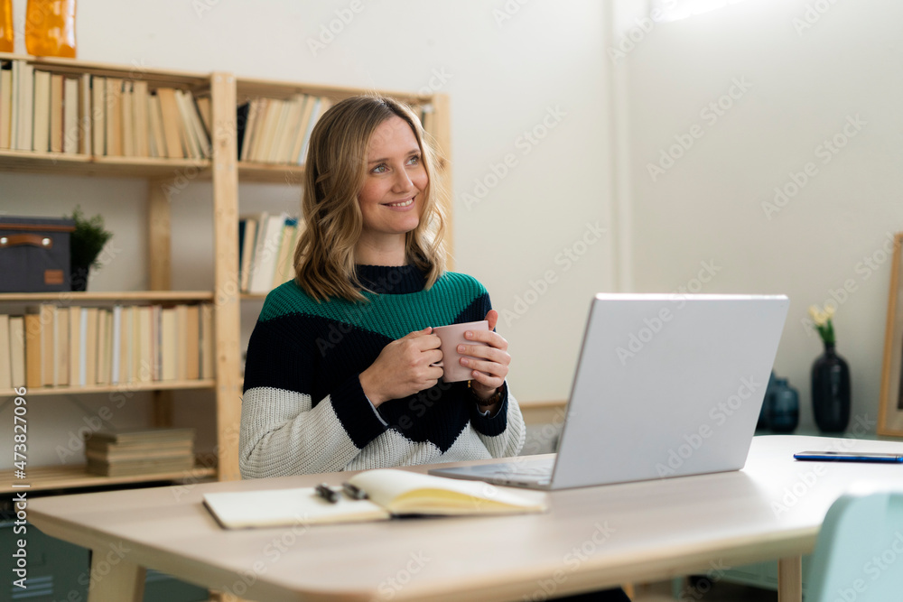 Thoughtful woman with coffee cup sitting at home Thoughtful woman with coffee cup sitting at home