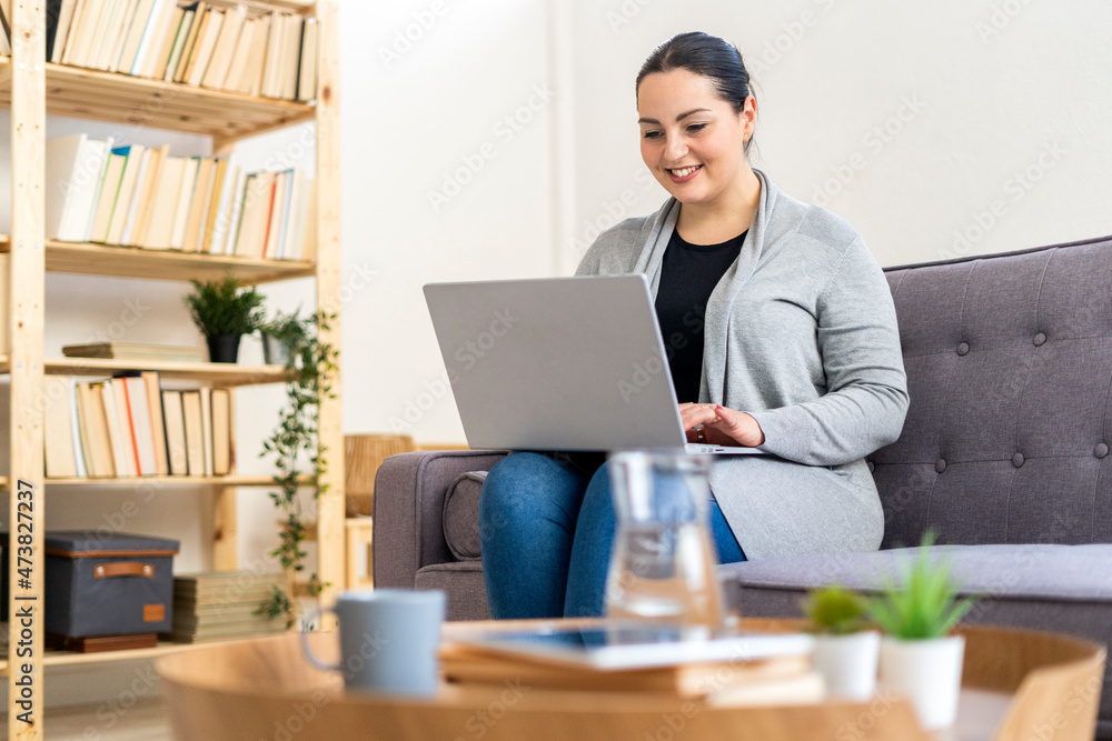 Smiling woman using laptop in living room at home Smiling woman using laptop in living room at home