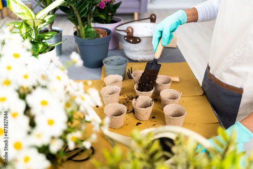 Female florist putting soil in flower pot at plant shop photo