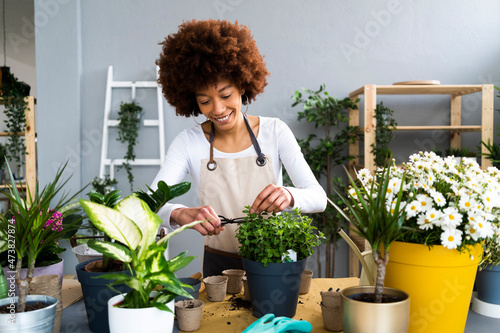 Smiling female florist pruning potted plant at shop