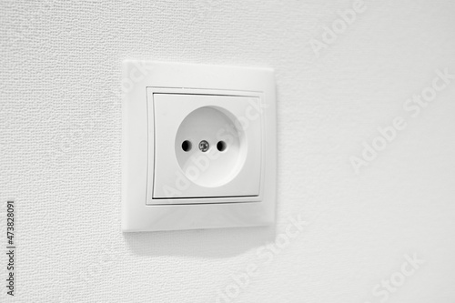 German circular recess socket with two round holes for 2 pins europlugs types C, E and F. Common cheap plastic AC power wall outlet. Not grounded European white electrical socket CEE 7 against wall