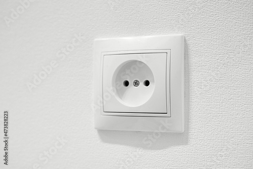 Common cheap plastic AC power wall outlet. German circular recess socket with two round holes for 2 pins europlugs types C, E and F. Not grounded European white electrical socket CEE 7 against wall