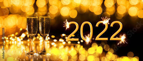 2022 New Year. Happy new year 2022 greeting card. Champagne glasses on glitter background © meegi