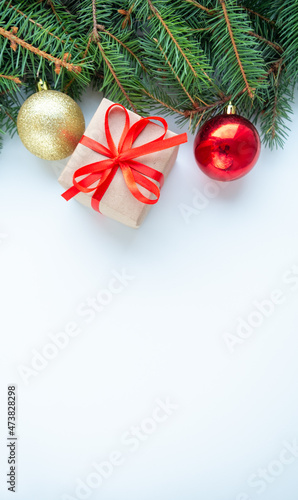 Merry Christmas and Happy New Year white background with green fir branches, balls and gift. Christmas tree flatly. Flat lay, top view, copy space for text. © Elena