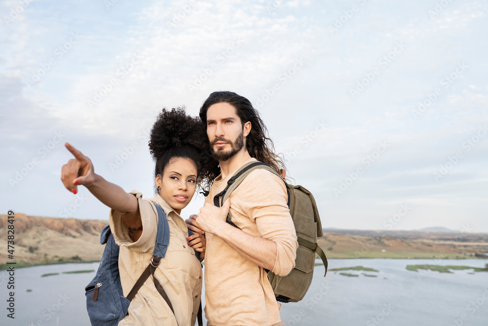 Girlfriend with backpack pointing while standing by boyfriend Girlfriend with backpack pointing while standing by boyfriend