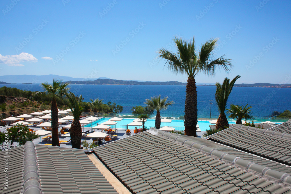 Fototapeta premium View from the gray roof of the swimming pool near the sea. Near the pool there are sun loungers and umbrellas.