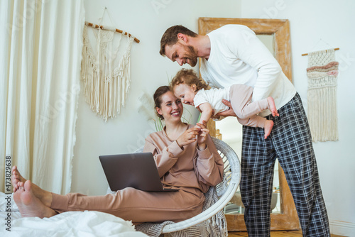 Smiling woman holding daughter's hand while carried by man at home