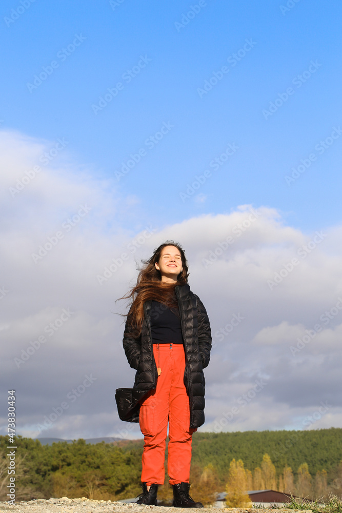 a young girl stands in nature on a sunny day